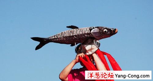 一位表演完渔舞的渔民，用大渔模型遮阳。