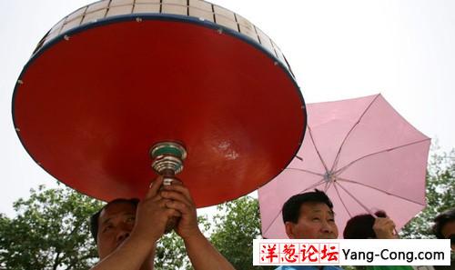 北京，毒辣的阳光，让一位老汉举起了巨大的空竹当遮阳伞。